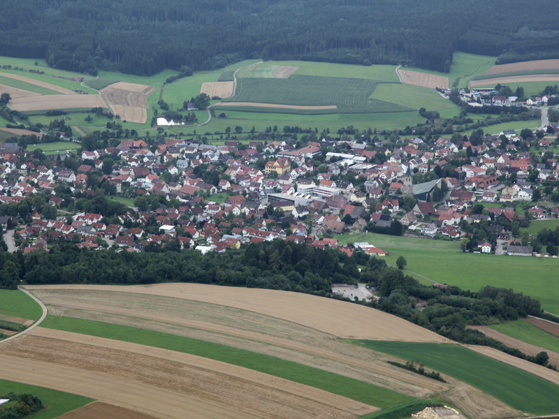 Die Gemeinde von oben mit vielen Gebäuden und grün rings rum